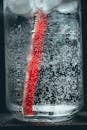 Close-up of soda water in glass with bubbles and red straw, refreshing drink concept.